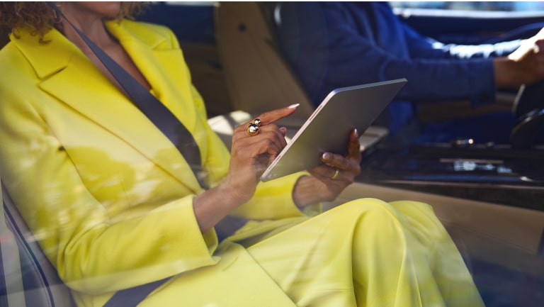 Plano medio de una mujer sentada en el asiento del acompañante de un vehículo Chevrolet utilizando una tablet.
