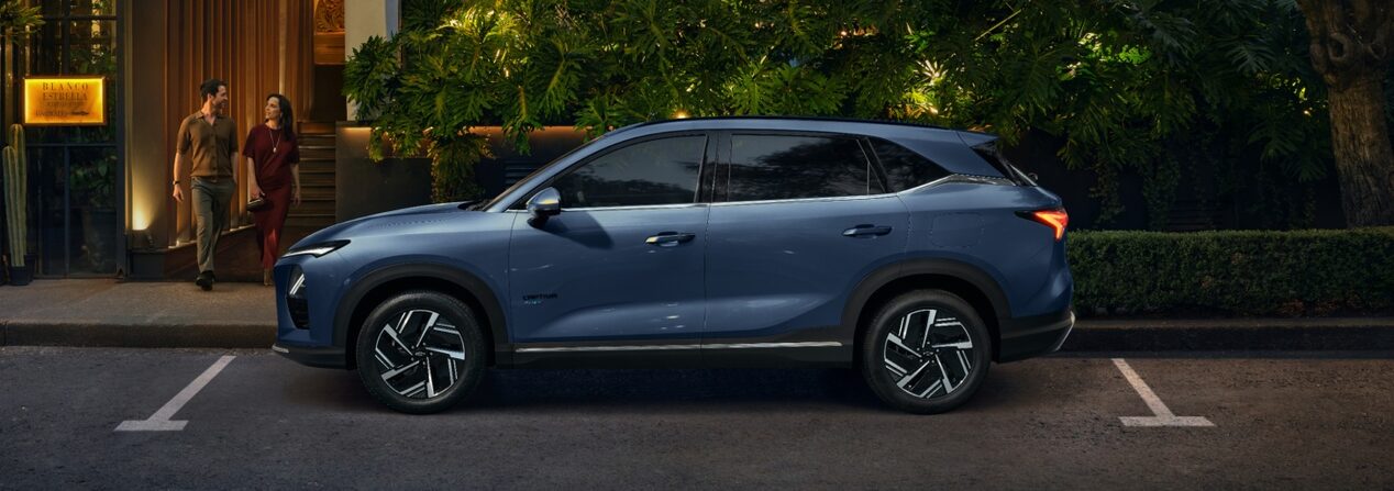 Vista lateral de la Chevrolet Captiva PHEV estacionada en la puerta de un restaurante, mientras un hombre y una mujer salen por la puerta del local.