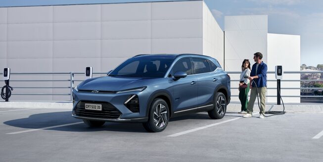 Imagen de un hombre y una mujer a punto de cargar una Chevrolet Captiva PHEV estacionada en una playa de estacionamiento con cargadores eléctricos.