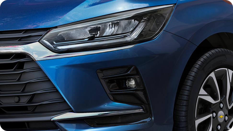 Detalhe da lanterna dianteira do Chevrolet Onix com badge “Turbo” em destaque, na cor Prata Shark.