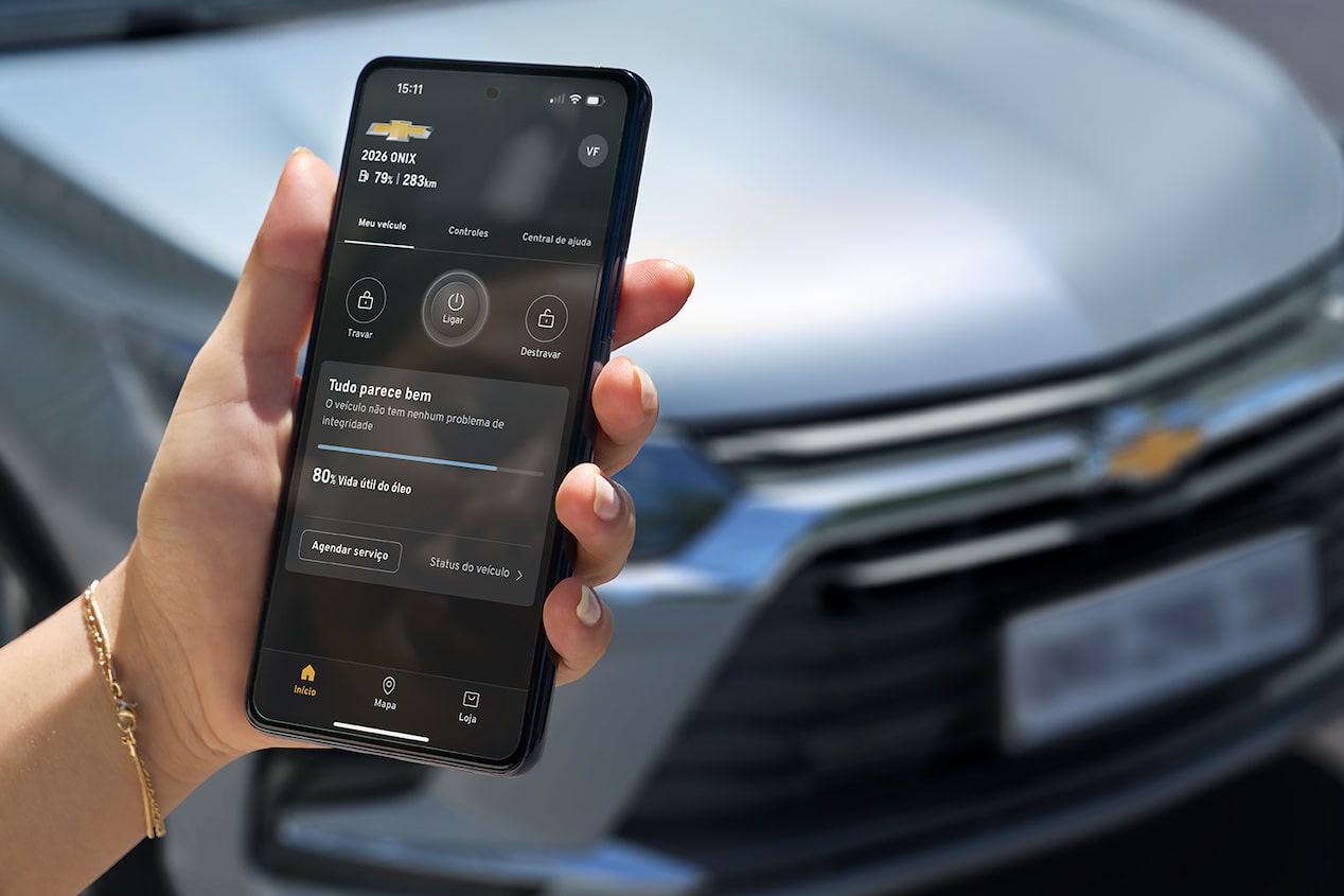 A mão de uma pessoa utilizando o celular em frente a um Chevrolet.