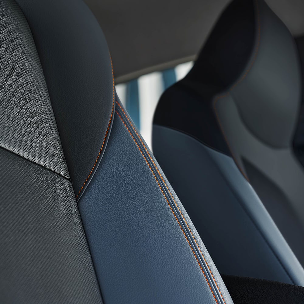 Detalhe do banco traseiro do Onix Plus com costura contrastante em laranja e acabamento escuro.