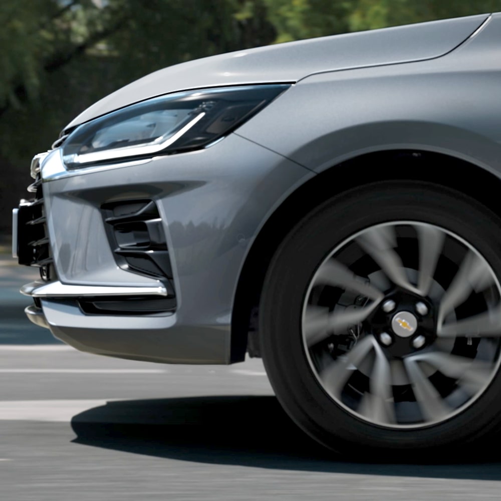 Close da roda dianteira do Onix Plus com farol parcialmente visível.