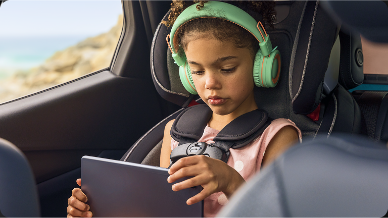 Criança com um tablet e fones de ouvido dentro de um carro
