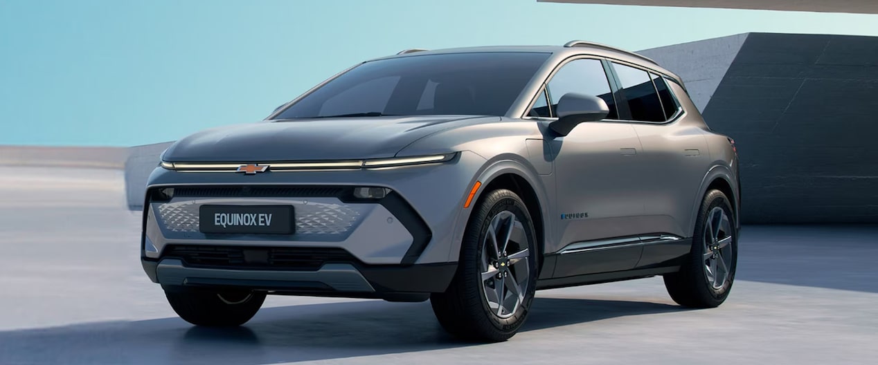 Equinox EV em imagem ambientada, estacionado diante de uma edificação com arquitetura assinada, fazendo com que as linhas do veículo sejam continuadas pelas linhas do prédio.