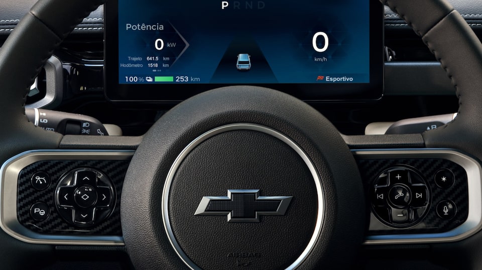 Close no painel de instrumentos digital e no volante com o logo Chevrolet ao centro, evidenciando a interface tecnológica do SUV elétrico.