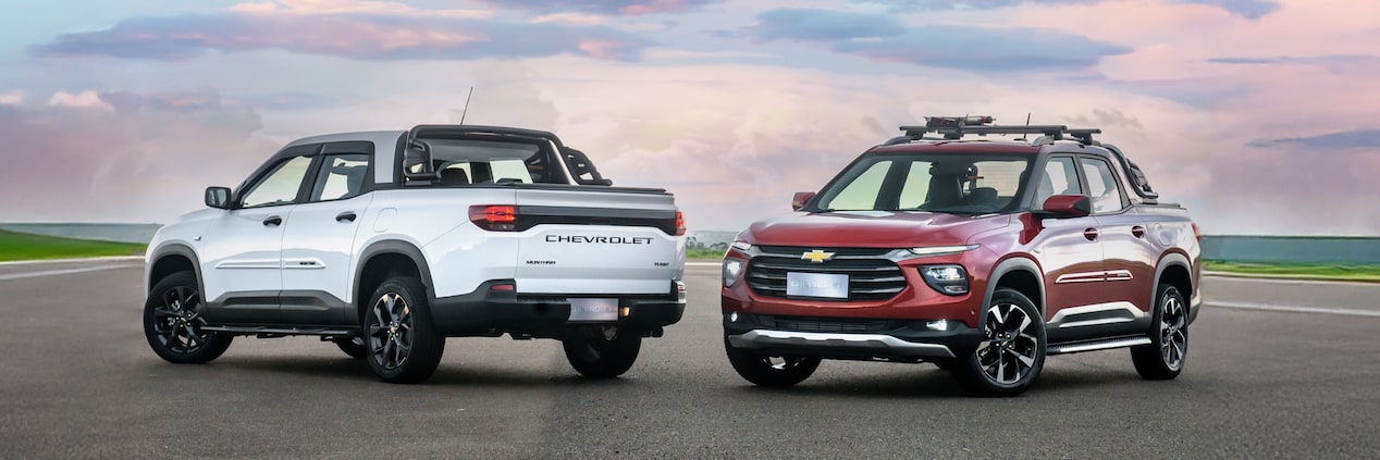 Chevrolet Montana branca e Chevrolet Montana vermelha em foto ambientada, estacionadas uma de frente para a outra a céu aberto. No quadrante superior esquerdo, o texto: Montana - acessórios.