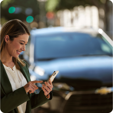 Mulher com celular na mão e um carro ao fundo
