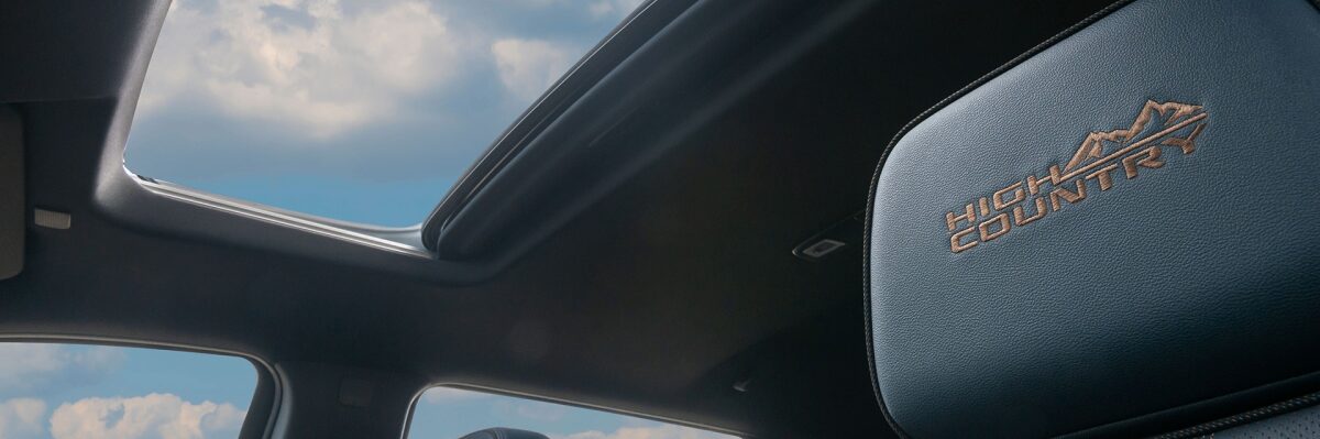 Detalhe do logo High Country no banco do motorista encimado pelo teto solar panorâmico da Chevrolet Silverado a para a página de acessórios originais da respectiva picape.