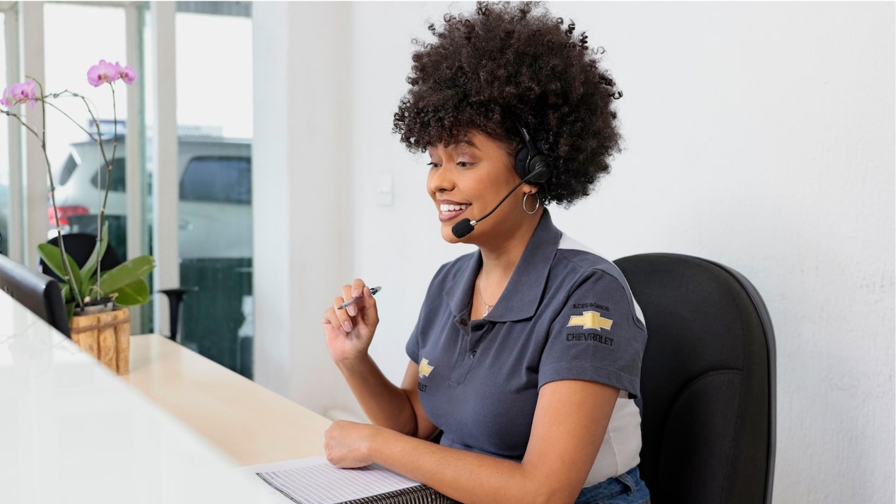 Atendente Chevrolet sentada à mesa em uma das concessionárias da rede