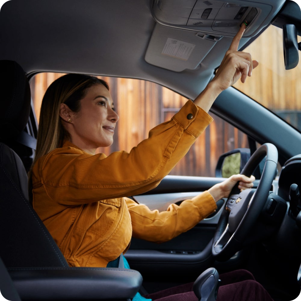 Mujer sentada en el asiento del conductor, utilizando OnStar desde su vehículo Chevrolet.