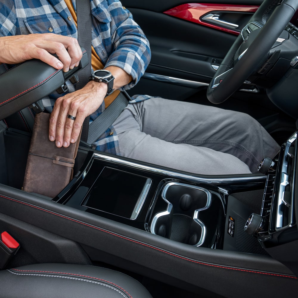 Imagen que muestra un hombre sentado en el asiento de conductor de la Chevrolet Traverse Z71,  mientras guarda su billetera en el compartimiento central debajo de los apoyabrazos.