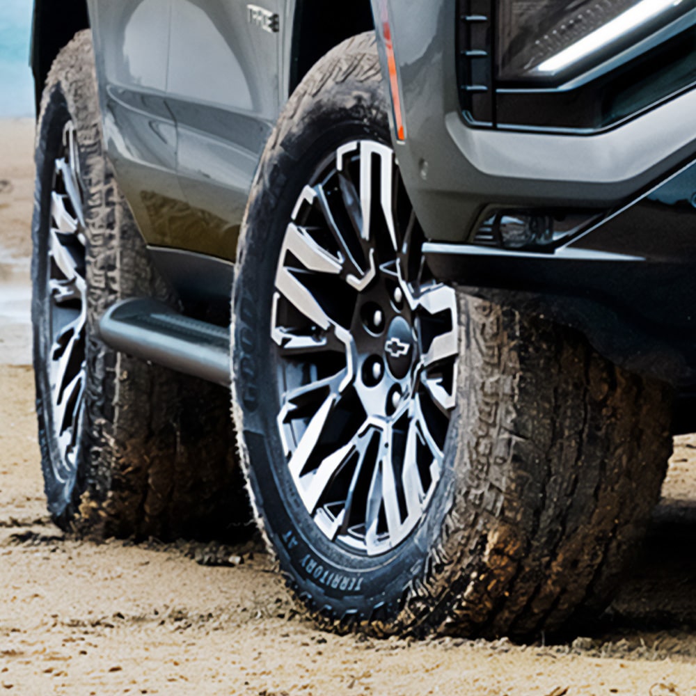 Vista en detalle en las llantas delanteras de 20" de la Chevrolet Tahoe sobre la arena.
