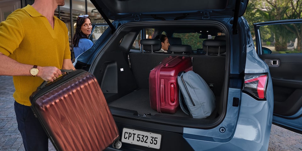 Familia alistando maletas en el baúl de una Chevrolet Captiva híbrida enchufable, destacando su espacio de carga, comodidad y diseño ideal para viajes en carretera.