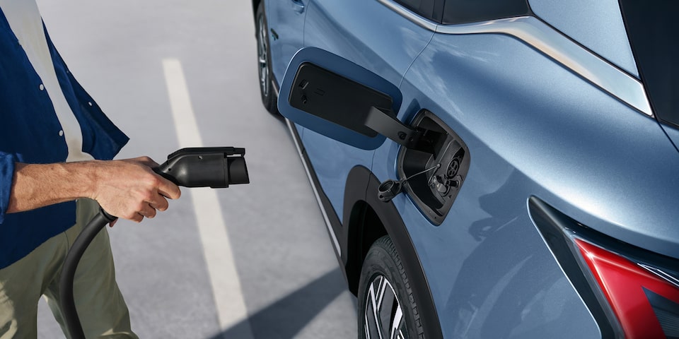 Persona conectando el cargador a una Chevrolet Captiva híbrida enchufable.