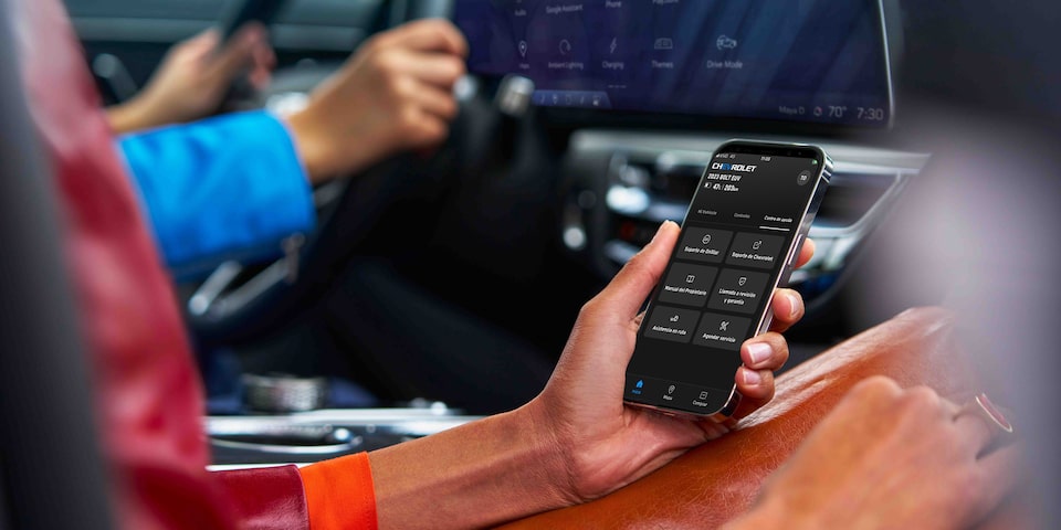 Persona usando la app móvil de Chevrolet para controlar funciones y seguridad del vehículo desde el interior del auto