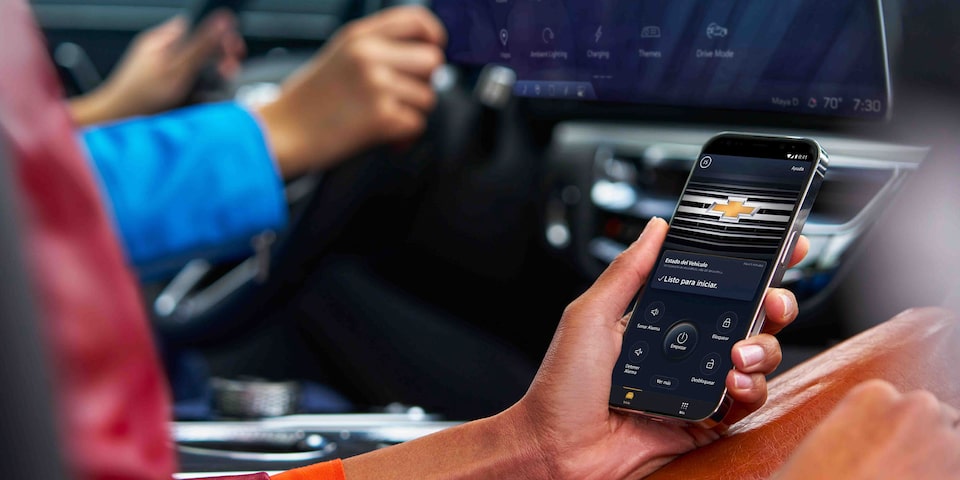 Persona usando la app móvil de Chevrolet para controlar funciones y seguridad del vehículo desde el interior del auto