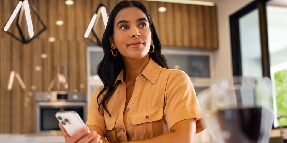 Mujer usando aplicación móvil de Chevrolet para controlar funciones de su vehículo desde casa