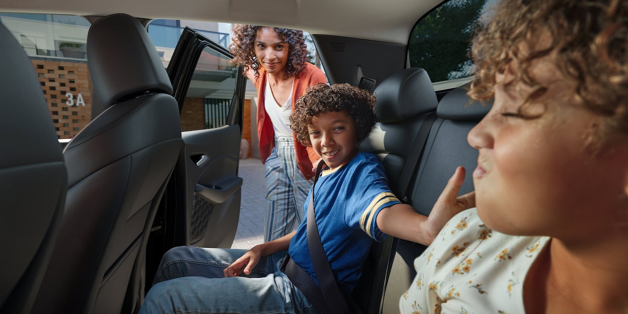 Dos niños sentados sonriendo y jugando en los asientos traseros de la Chevrolet Montana.