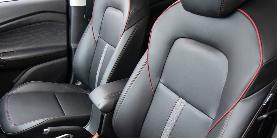 Interior de la Chevrolet Tracker 2025 con asientos de cuero, costuras rojas y diseño ergonómico para máximo confort
