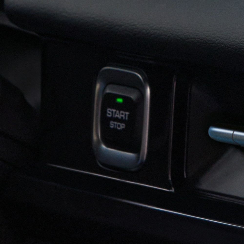 Botón de encendido sin llave de la Chevrolet Groove, con una luz verde encendida en su parte superior y las palabras START y STOP.