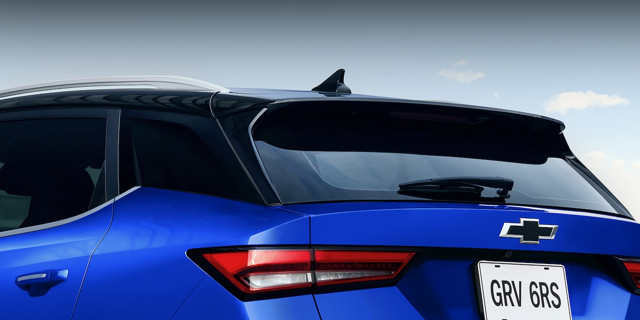 Vista de cerca de la parte trasera superior de la Chevrolet Groove RS, mostrando el alerón trasero, el limpiaparabrisas trasero, parte de los faros traseros LED y el emblema negro de Chevrolet. En la matrícula se lee GRV 6RS.