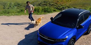 Chevrolet Groove estacionada sobre la cima de un mirador, vista desde arriba, junto a un hombre y su perro corriendo a un costado. 