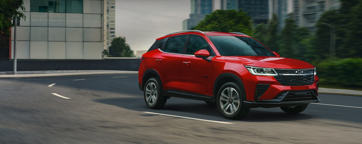 Nueva Chevrolet Groove circulando por carretera urbana, con edificios y árboles de fondo. 