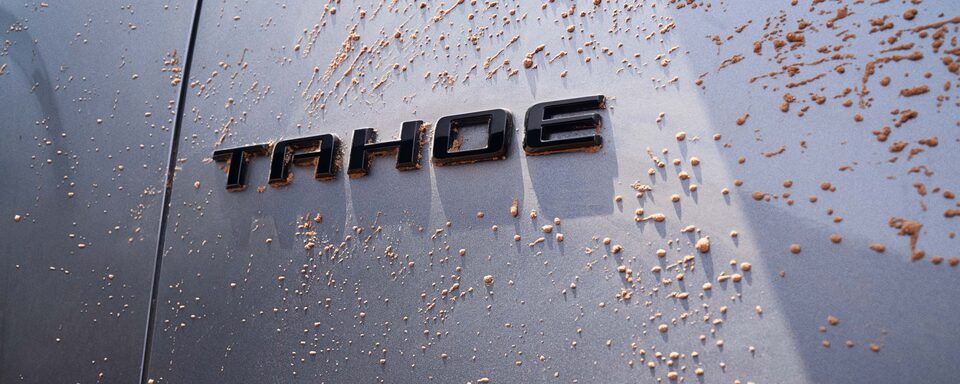 Detalle del logo Chevrolet Tahoe cubierto de barro, representando su resistencia en condiciones todoterreno