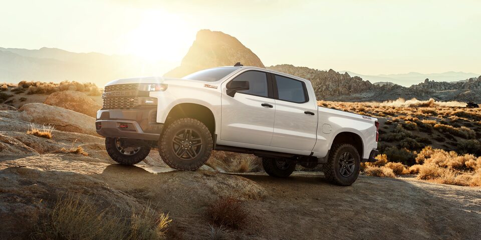 Chevrolet Silverado subiendo por una piedra, rodeada de montañas y naturaleza.