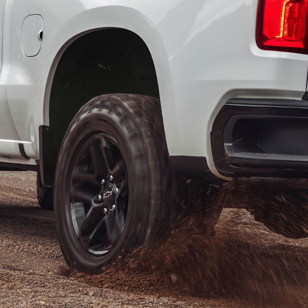 Vista trasera de una Chevrolet Silverado andando sobre camino de ripio.