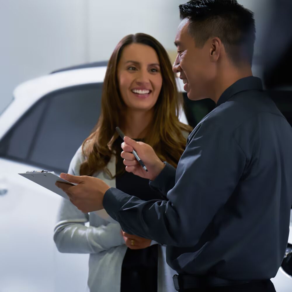 Asesor de servicio atendiendo a una clienta en un concesionario Chevrolet.