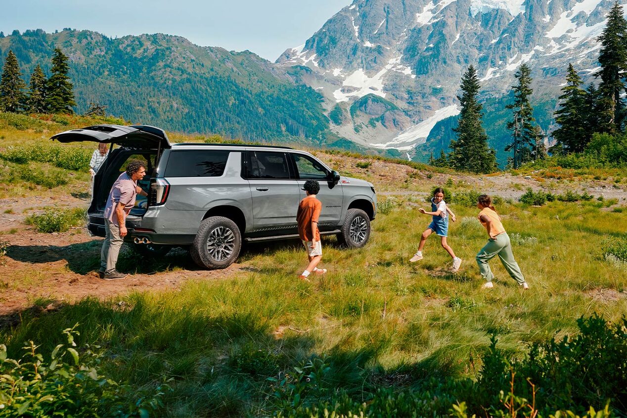 Chevrolet Suburban con una familia jugando alrededor.